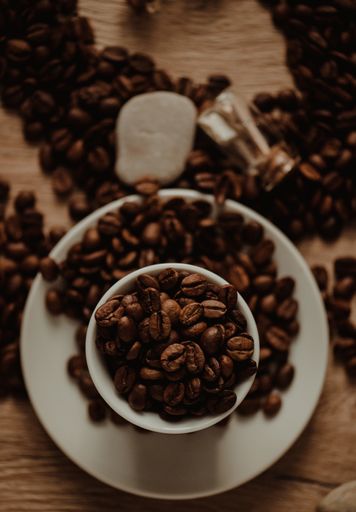 A top view of a coffee cup with roasted beans on blurred background