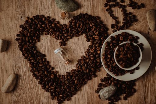 A top view of a cup full of coffee beans and heart-shaped sign from coffee beans