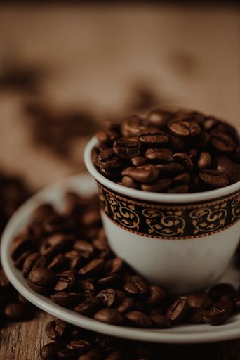 A vertical shot of a coffee cup with roasted beans on blurred background
