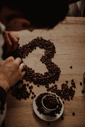 A top view of a cup full of coffee beans and heart-shaped sign from coffee beans