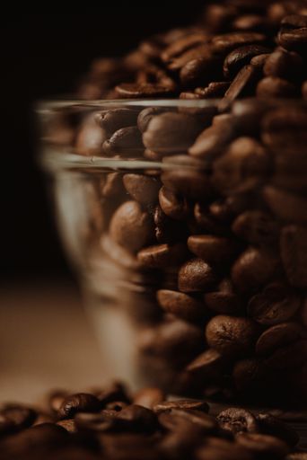 A closeup shot of aromatic coffee beans in a glass bowl on blurred background