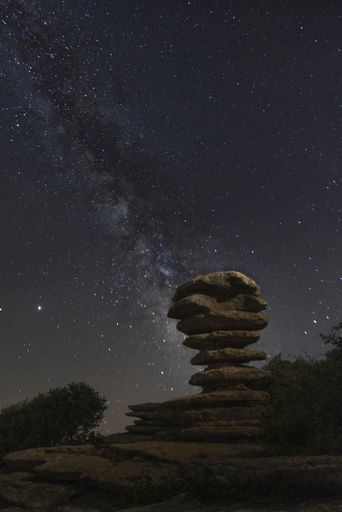 A vertical shot of rocky formation under starry night sky