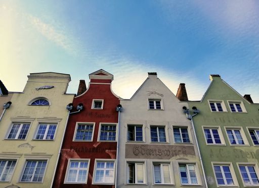 A low angle shot of the colorful houses in Gdansk, Poland with thin clouds background