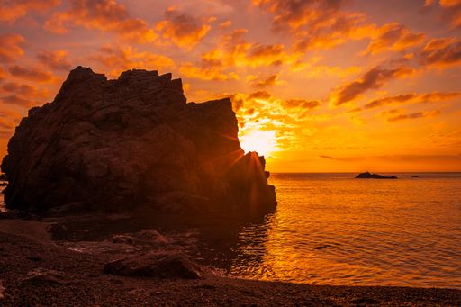 The rocks and cliffs on the Golfet beach surrounded by the sea during a golden sunset in Calella de Palafrugell, Spain