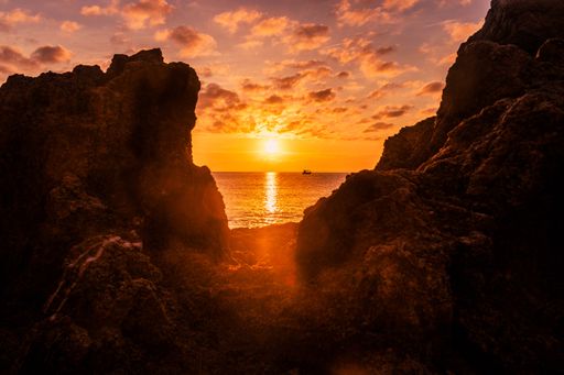 The rocks and cliffs on the Golfet beach surrounded by the sea during a golden sunset in Calella de Palafrugell, Spain