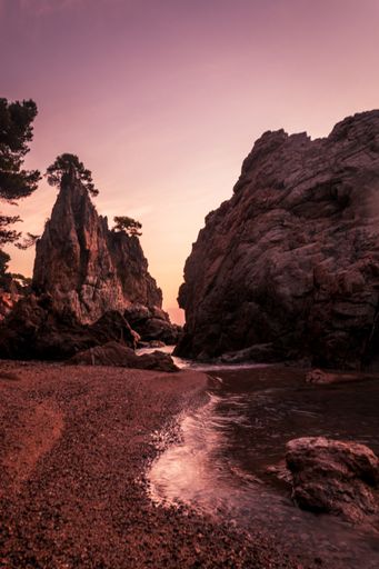 A vertical shot of rocks and cliffs on the Golfet Beach during a beautiful sunset in Calella de Palafrugell, Spain