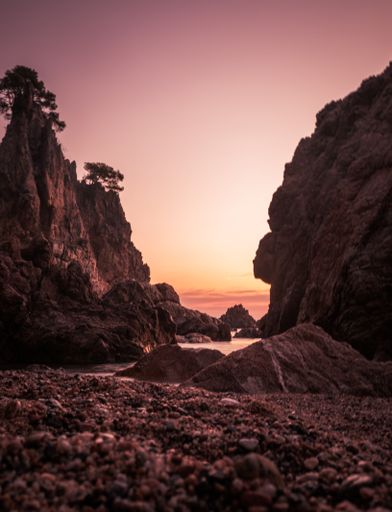A vertical shot of rocks and cliffs on the Golfet Beach during a beautiful sunset in Calella de Palafrugell, Spain