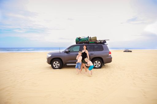 A beautiful shot of a Caucasian mother posing with her sons on a sandy beach - weekend with family