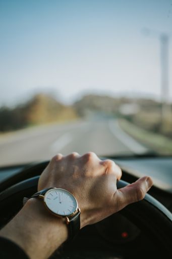 A vertical shot of a male driver hand on the steering wheel