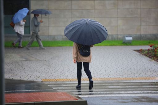 A shallow focus shot of a female holding an umbrella while walking on a rainy weather