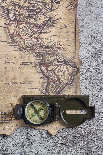 A top view closeup of a compass placed on an ancient map
