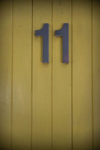 A vertical shot of the number 11 on a yellow wall