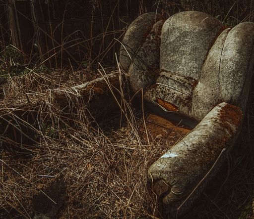 A closeup shot of an old and dirty sofa and dry branches on it in a dark room