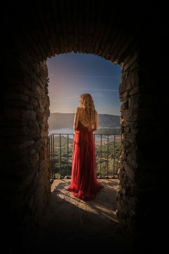A scenic vertical shot of an attractive female posing in the balcony of an old fortress