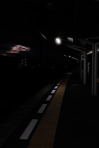 A vertical shot of an empty railroad station during a dark sunset