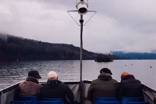 A river with a boat of tourists on it with rocky mountains covered with a fog in the background