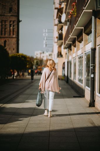 A vertical shot of a girl walking on the street on a sunny day