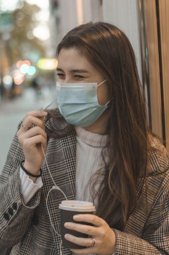 A young cute female talking on phone and holding a plastic cup of coffee