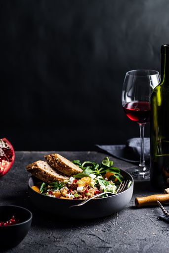 A salad with lamb's lettuce, goat cheese, mandarine and spring onion and red wine, vertical shot