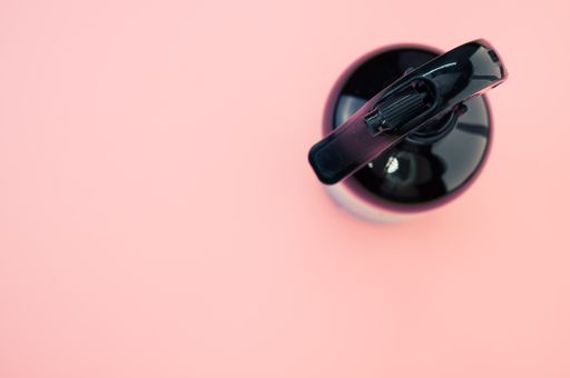 A high angle shot of a plastic spray bottle isolated on a pink background