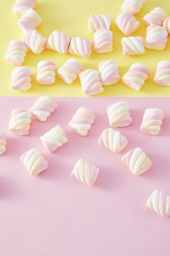 A top view closeup of colorful marshmallows isolated on a yellow and pink background