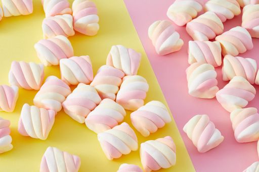 A top view closeup of colorful marshmallows isolated on a yellow and pink background