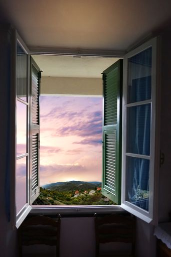 A vertical shot of a room window overlooking a village on a cloudy day