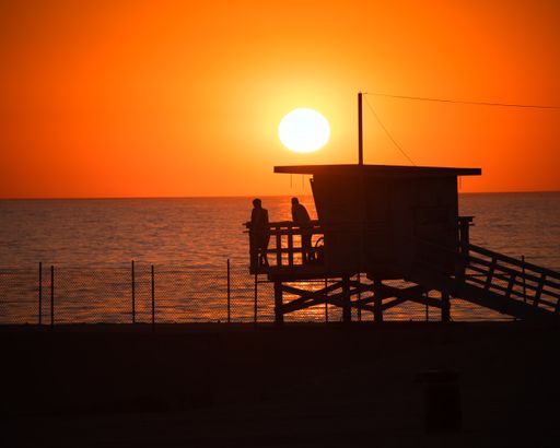 A beautiful shot of people watching the sea from a lifeguard spot during an orange sunset