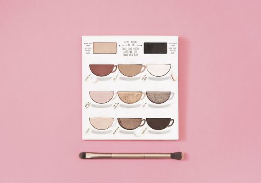 A closeup shot of an eye shadow palette with brushes on pink background