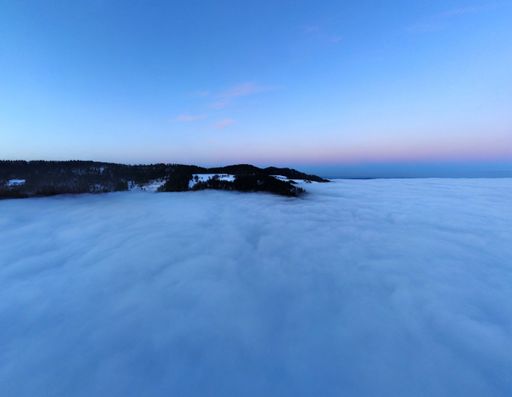 A scenic view of the mountain peak covered with snow and trees above the sky