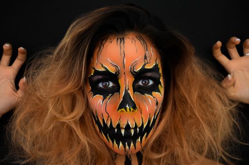 A young female with Halloween makeup over dark background