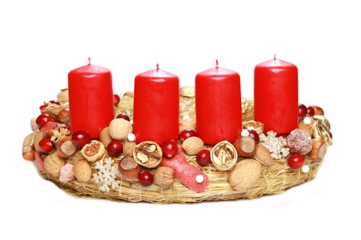 A closeup of an advent wreath with red candles and walnuts isolated on a white background