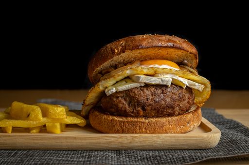 A closeup of fresh tasty homemade beef burger and french fries on a wooden tray
