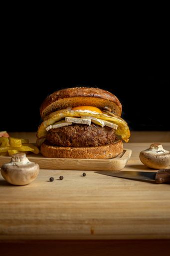 A closeup of fresh tasty homemade beef burger and french fries on a wooden tray