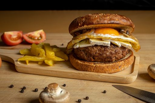 A closeup of fresh tasty homemade beef burger and french fries on a wooden tray