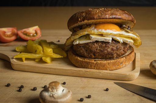A closeup of fresh tasty homemade beef burger and french fries on a wooden tray