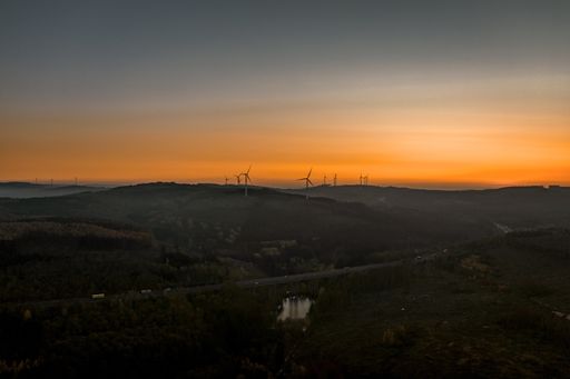 An aerial view of wind power plants in a mountainous area during sunset