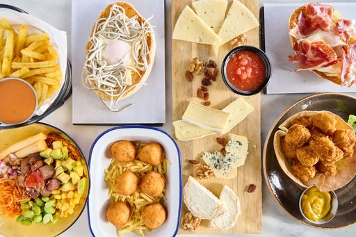 A top view of a variety of fried delicacies and appetizers alongside a cheese platter