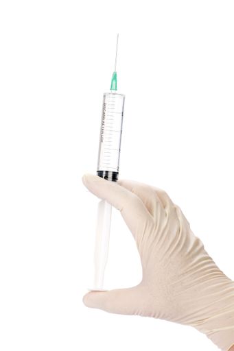 A vertical closeup shot of a doctor/nurse holding a syringe on a white background