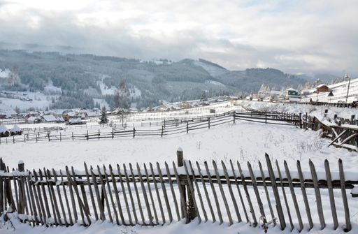The wooden fences in a rural area in winter with hills in the background