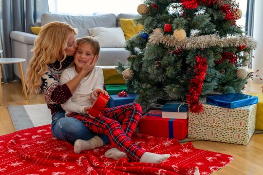 A closeup of a happy mother kissing her daughter, Christmas mood in a cozy house