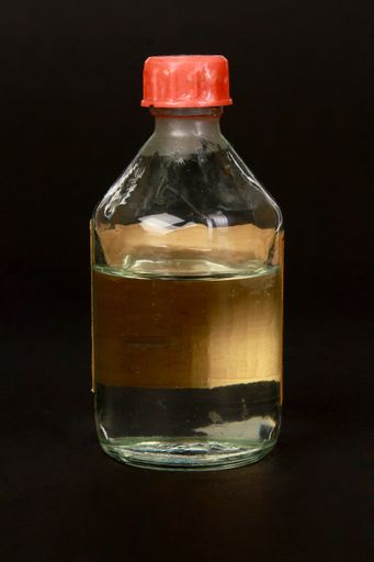 A vertical closeup shot of liquid medicine in a glass bottle isolated on a black background
