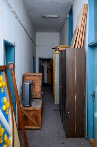 A vertical shot of a narrow hallway with old furniture in an abandoned building