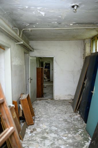 A vertical shot of an abandoned old building with a damaged ceiling and dirty ground
