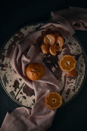 A top view of a rustic old circle board with mandarin orange fruits