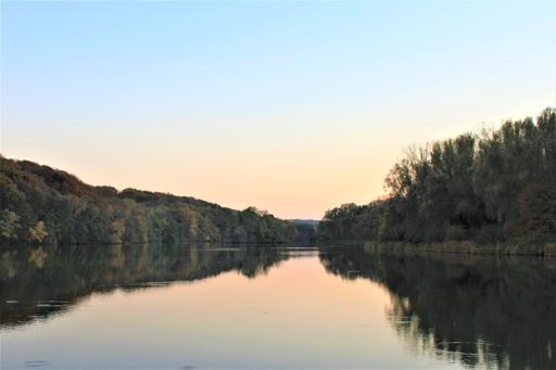 The autumn trees reflecting on the lake during sunset