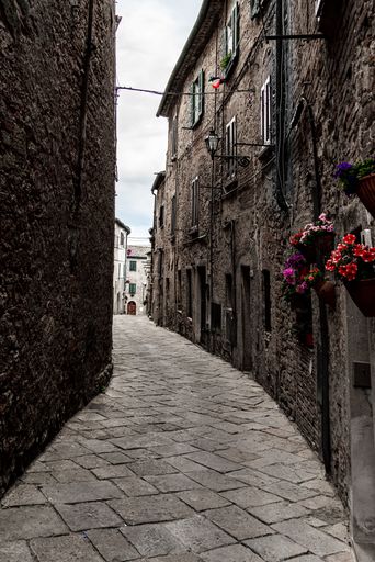 A narrow street between the old stone houses of ancient, historical town in the Volterra, Italy