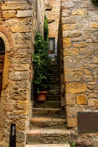 A narrow street between the old stone houses of ancient, historical town in the Volterra, Italy