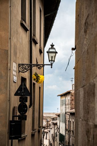 A narrow street between the old stone houses of ancient, historical town in the Volterra, Italy