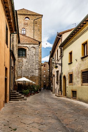 A narrow street between the old stone houses of ancient, historical town in the Volterra, Italy